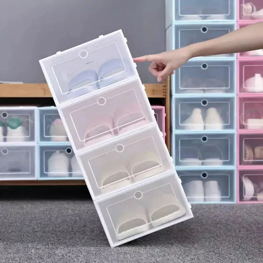 Stack of clear shoe boxes with a hand pointing to one, against a background of more shoe boxes.