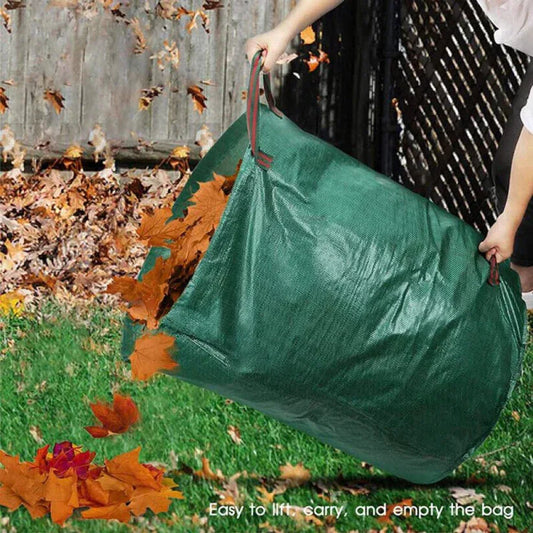 Person lifting a green leaf bag filled with autumn leaves outdoors.