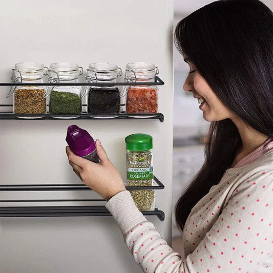 Woman reaching for a spice jar on a spice rack in a kitchen.