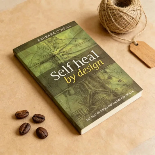 Book titled 'Self Heal by Design' by Barbara O'Neill on a textured surface with coffee beans and twine.