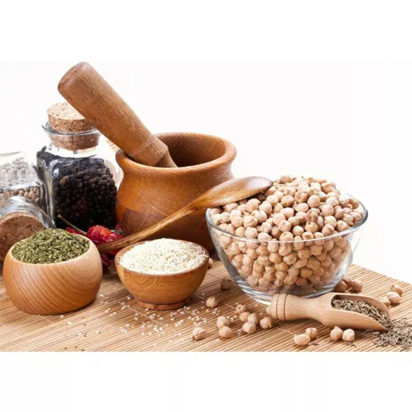 Spices, herbs, and a mortar and pestle on a wooden surface with a white background