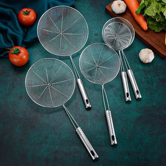 Set of four metal ladles with spider web patterns on a dark green surface with vegetables.