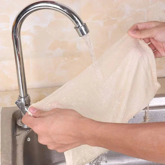 Person washing a white cloth under running water from a faucet.