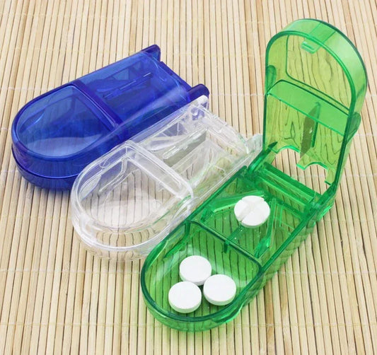 Split pill box with blue, green, and clear compartments on a bamboo mat.
