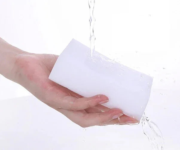 White sponge being held by a hand with water droplets on a white background