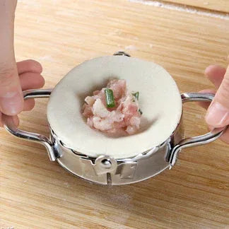 Handheld meatball maker with ingredients on a wooden surface

