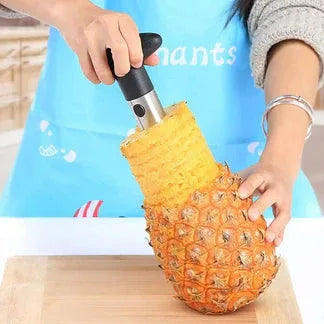 Person using a pineapple corer on a pineapple with a blue background

