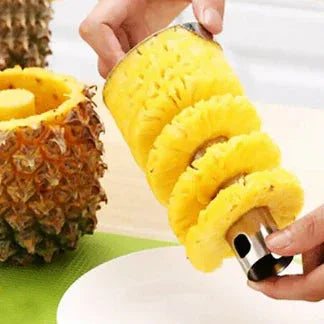 Pineapple slicer being used to cut a pineapple on a green surface.

