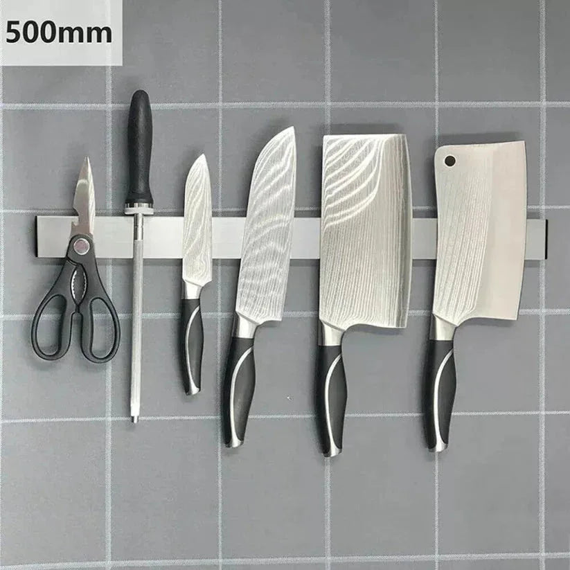 Set of knives and a pair of scissors on a magnetic strip with measurement label.

