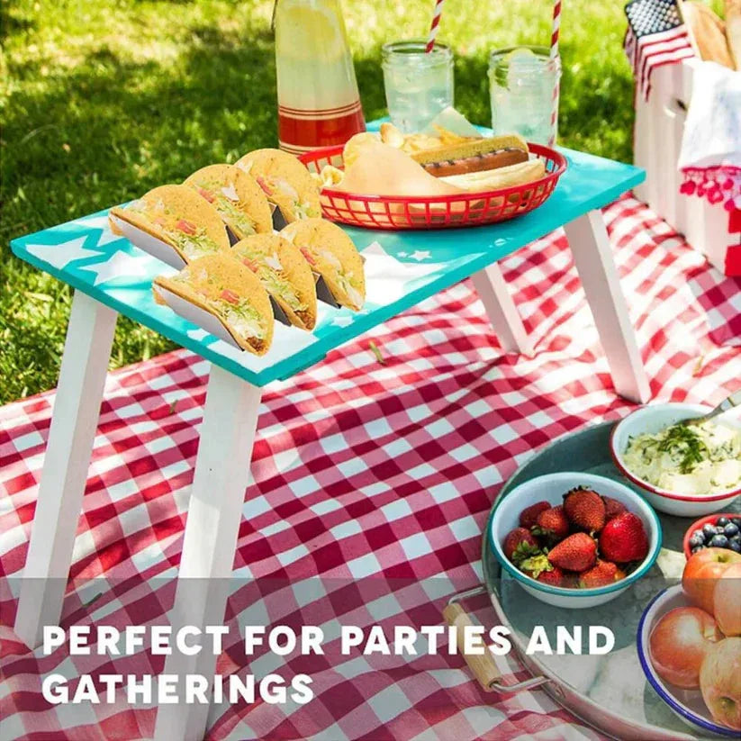 Outdoor picnic setup with food and drinks on a checkered blanket


