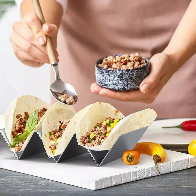 Person preparing tacos with a tortilla holder on a wooden table.

