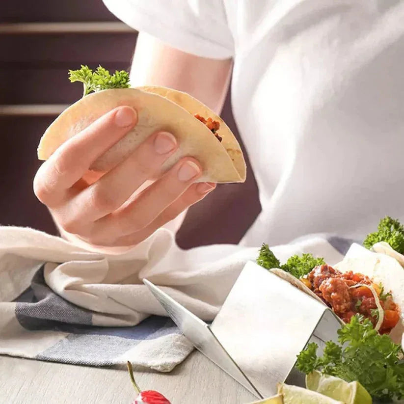 Person holding a taco with ingredients on a table

