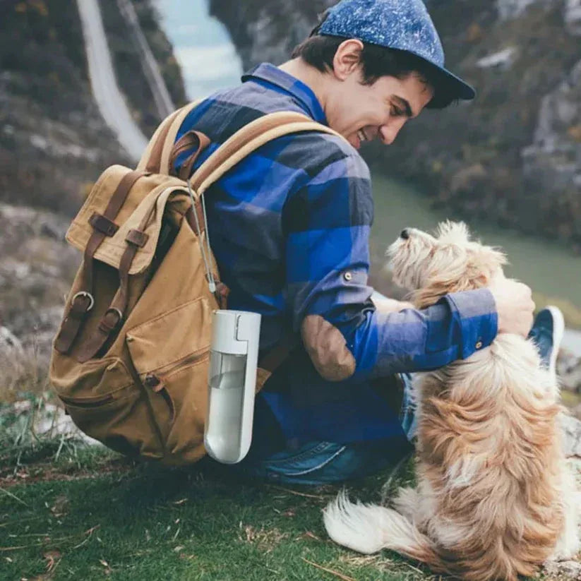 Person with a backpack petting a dog outdoors

