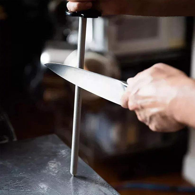 Person sharpening a knife on a whetstone with a blurred background

