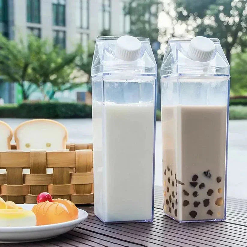 Two cartons of milk and a bubble tea on a wooden table with a blurred outdoor background.

