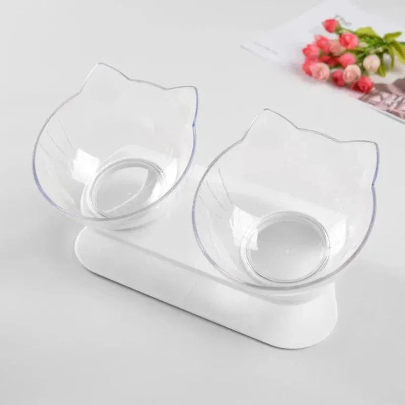 Cat-shaped double bowl feeder on a white surface with flowers in the background

