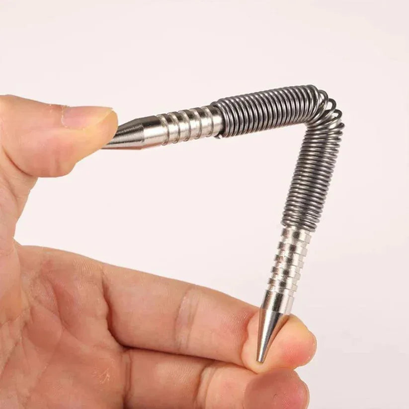 Metallic spring-like object held between fingers against a plain background

