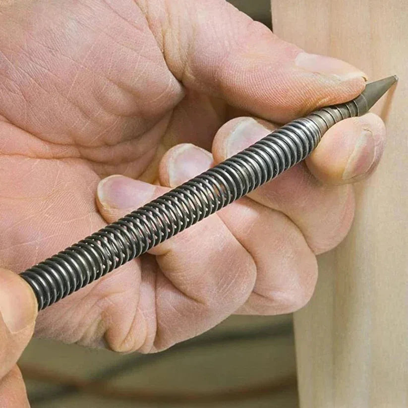 Hand holding a metal drill bit against a wooden surface

