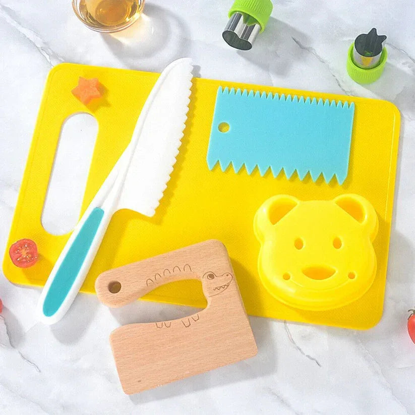 Set of colorful children's kitchen tools including a yellow cutting board, knife, and other utensils on a white surface.

