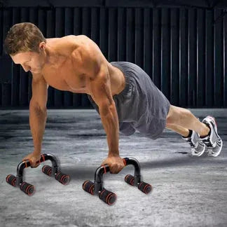 Man performing push-ups on a gray floor with a dark curtain background

