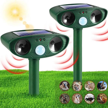 Two solar-powered animal deterrent devices on grass with a sun in the background.

