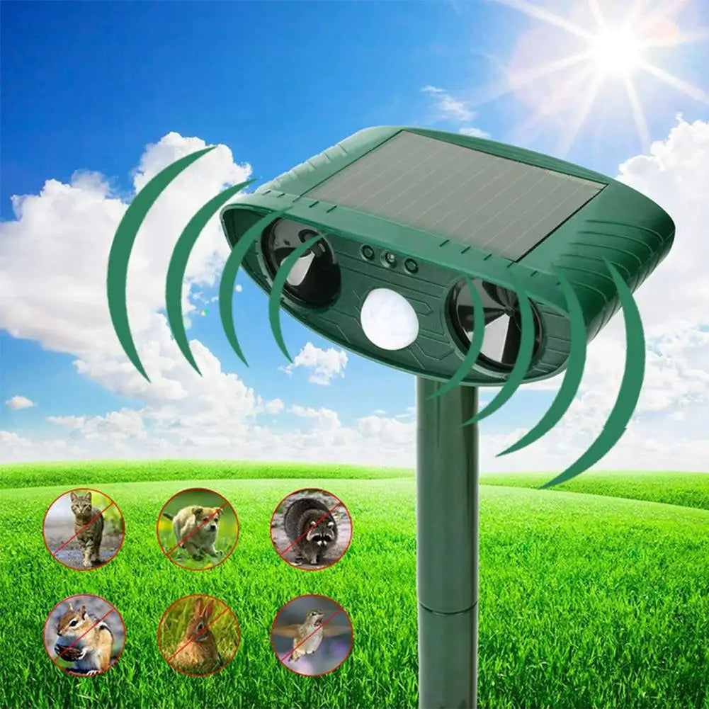 Solar-powered pest repeller with green spider design on a grassy field background

