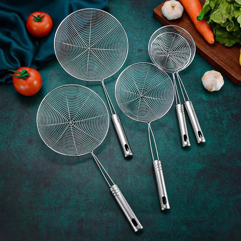 Set of four metal ladles with spider web patterns on a dark green surface with vegetables.

