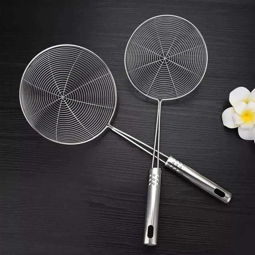 Two metal skillets on a dark surface with a white flower.


