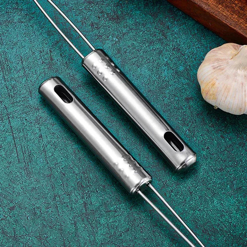 Two metal kitchen tools on a teal surface with garlic and a wooden block.

