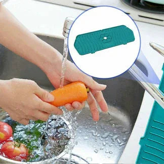 Person washing vegetables in a sink with a green silicone vegetable cleaner.


