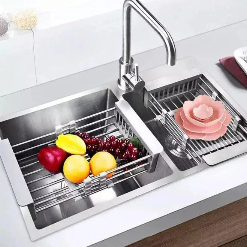 Stainless steel kitchen sink with fruit and vegetables on a white countertop

