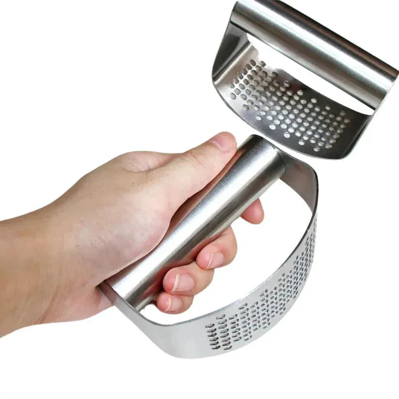 Hand holding a metal garlic press against a white background

