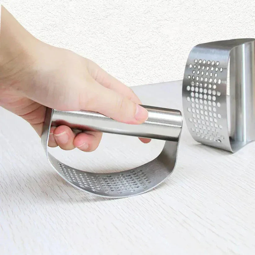 Hand holding a metal kitchen masher on a white background

